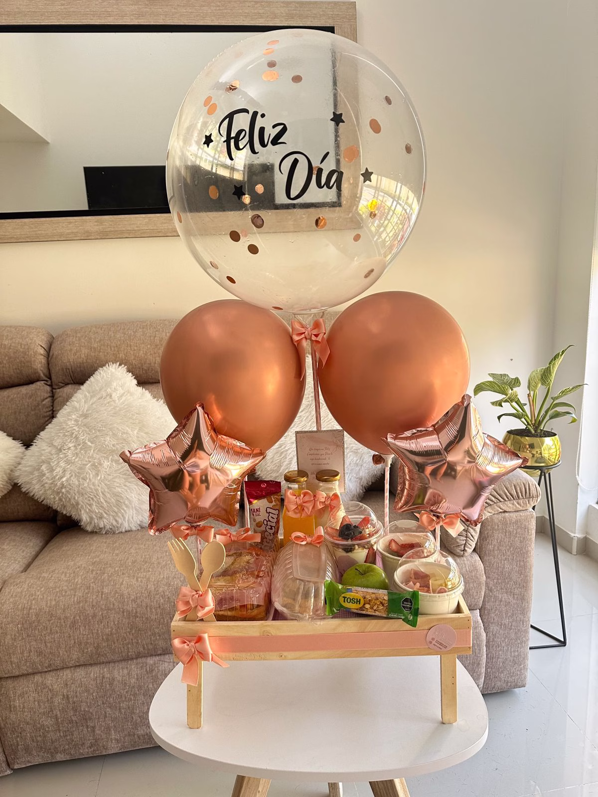 Desayuno sorpresa saludable en mesa de madera con globos y detalles en Bogotá