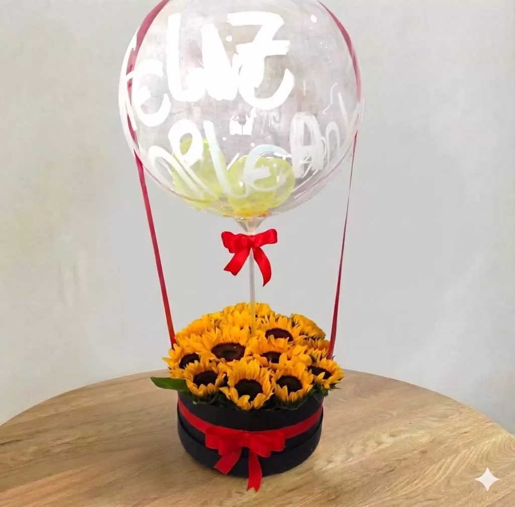 Tambor de cartón con 12 girasoles frescos y globo burbuja personalizado, arreglo floral a domicilio en Bogotá.
