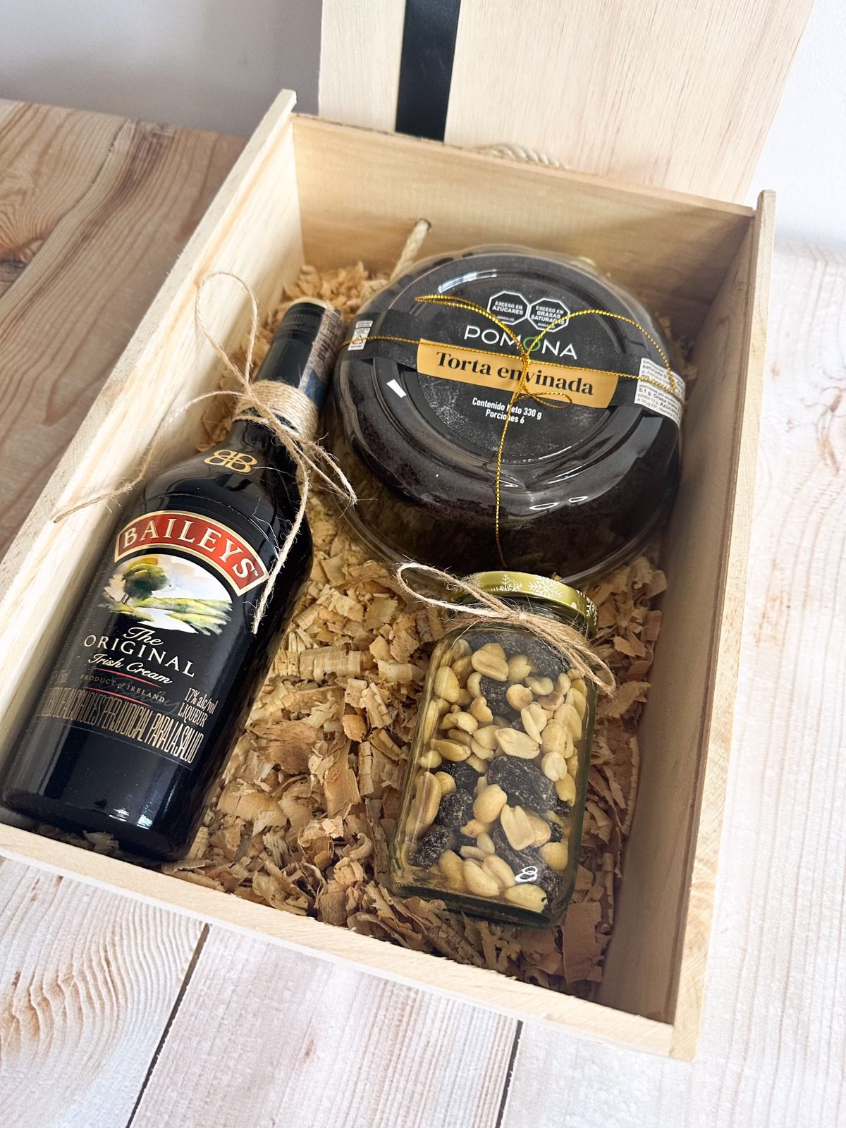 Ancheta corporativa Reserva Festiva con caja de madera, Baileys y torta negra en Bogotá.
